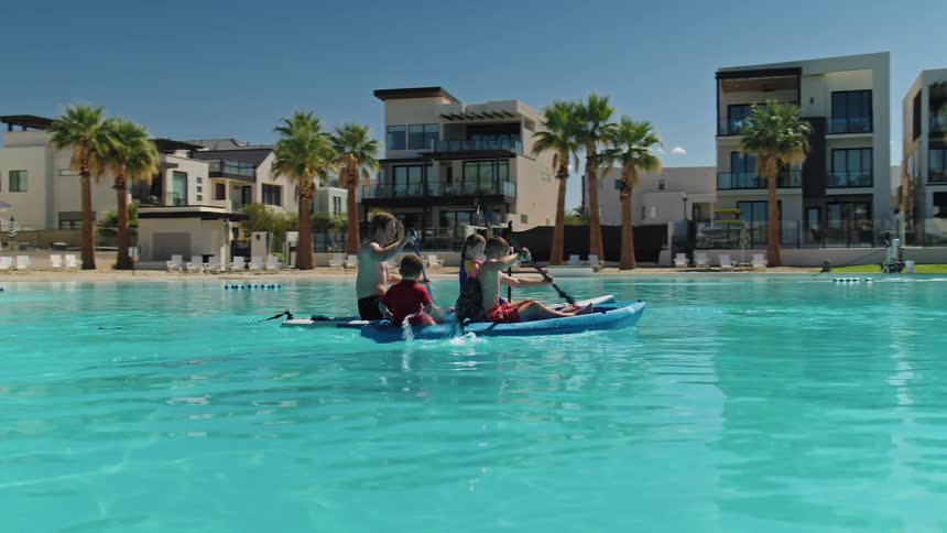 The kids row in kayaks in the pool on a sunny day
