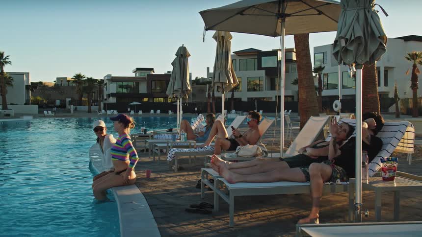 People relaxing on lounge chairs and by the pool at sunset