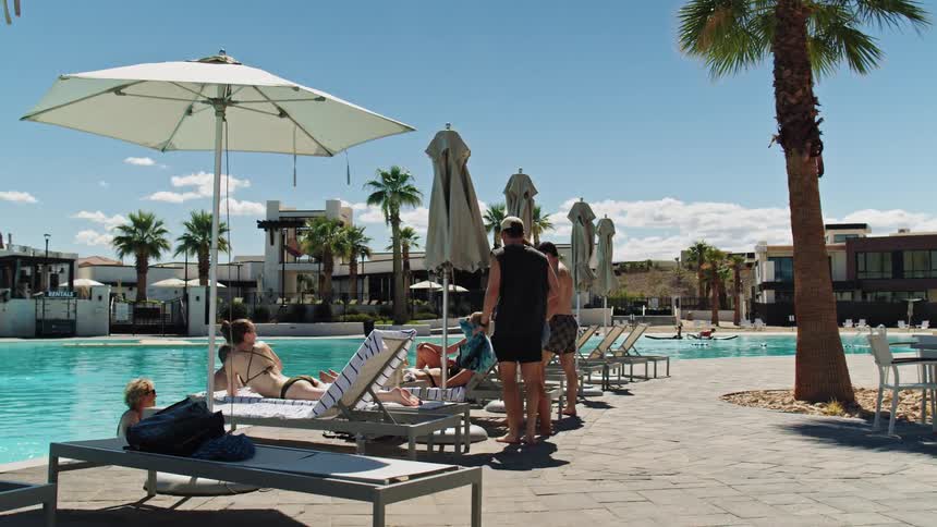 A group of people is at the side of a pool at a resort area
