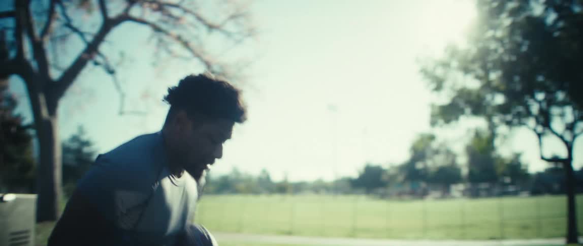 A man holding a football is doing exercise drills in a park
