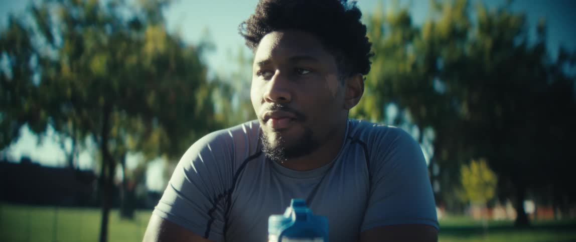 The man sits in the park by a water bottle