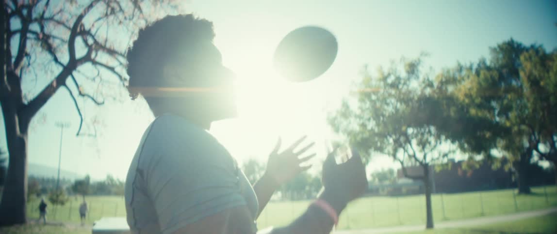A man is tossing a football from one hand to the other as he stands in a park