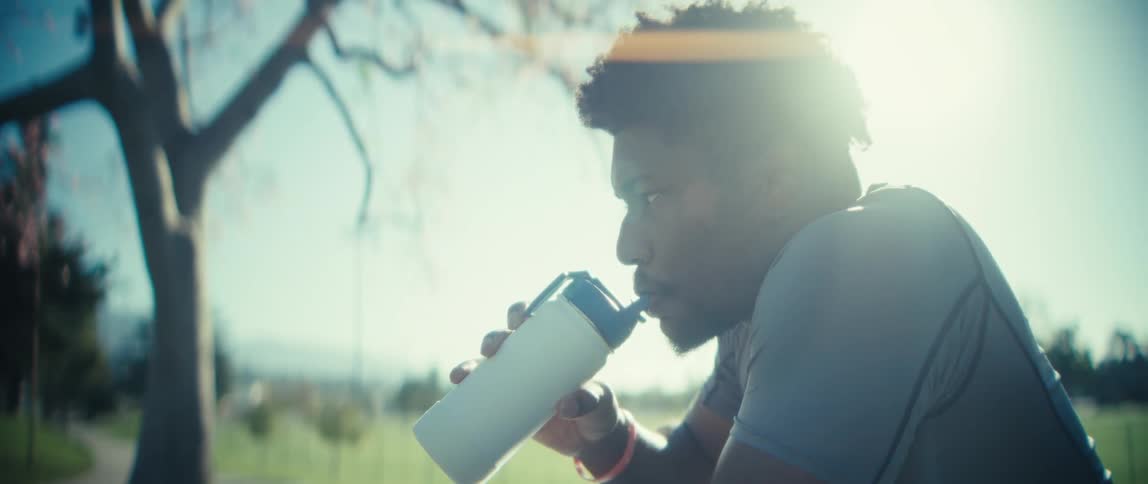The man drinks form a water bottle in the park