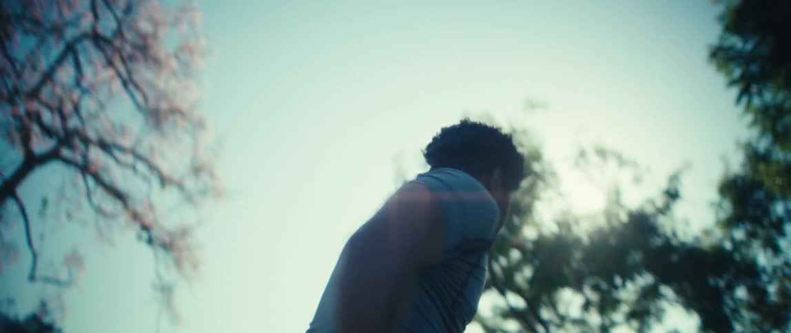 A man is holding a football and doing running exercises outside