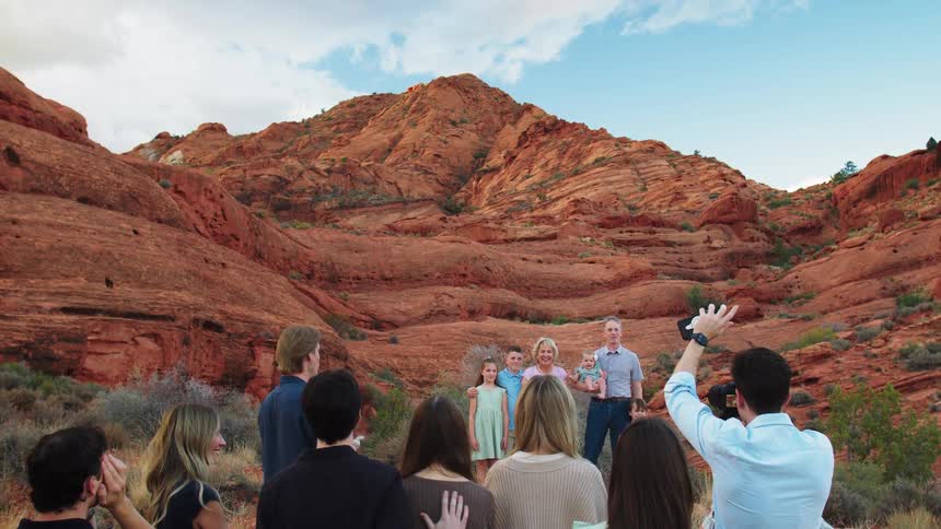 A group of people is standing outside near a mountain peak