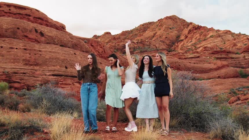 The women laugh and stand together by the mountain