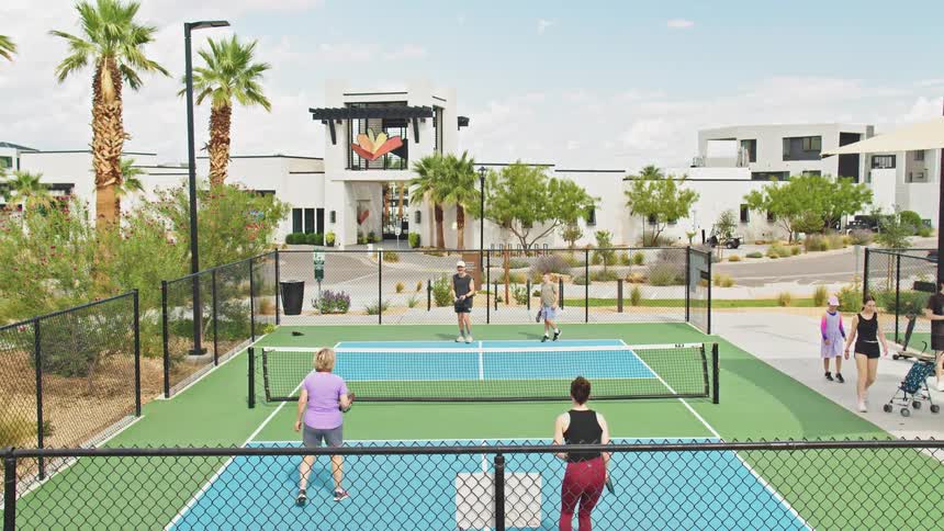 People play a game of pickleball in a sunny residential complex