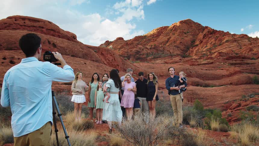 Group of people posing in a desert landscape with reddish mountains in the background