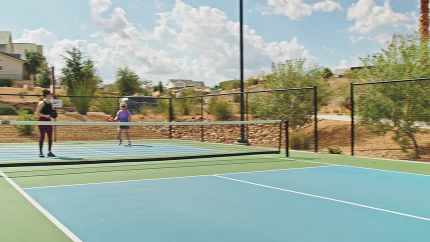 A father teams up with his son in a tennis match as the boy serves the ball toward their opponents two women on a sunny day at the tennis court