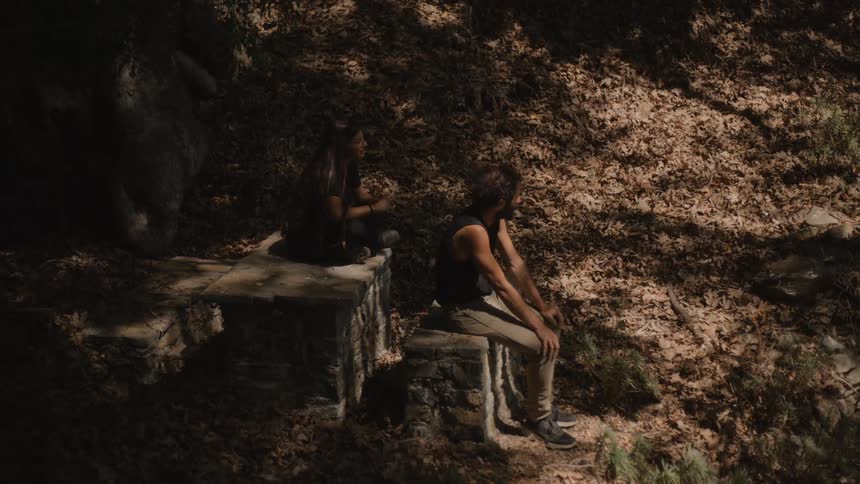 The man and woman sit in the shade of the forest
