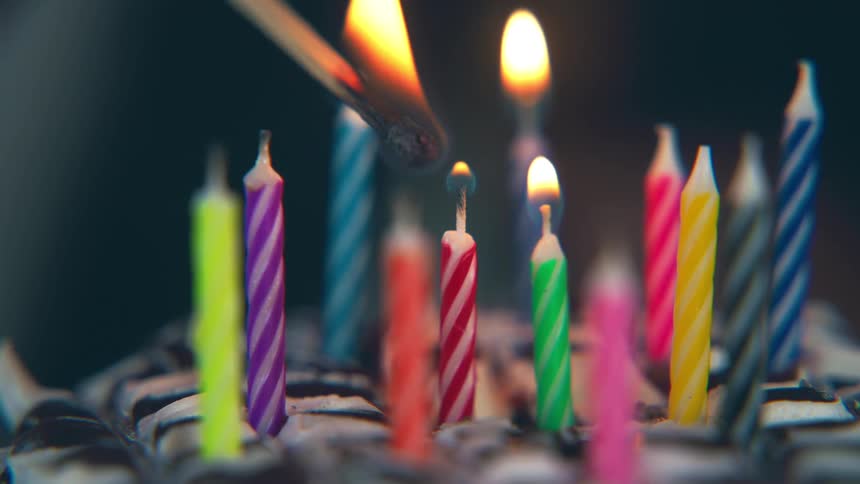 Colorful candles are lit on a birthday cake
