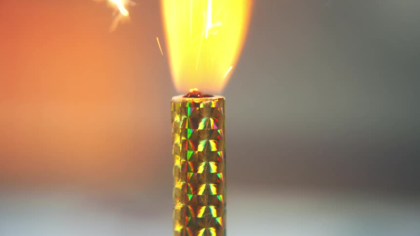 Match lighting a golden fountain candle with bright sparks