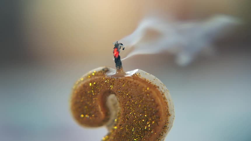 Smoking wick marks the end of the flame on a golden numbershaped candle