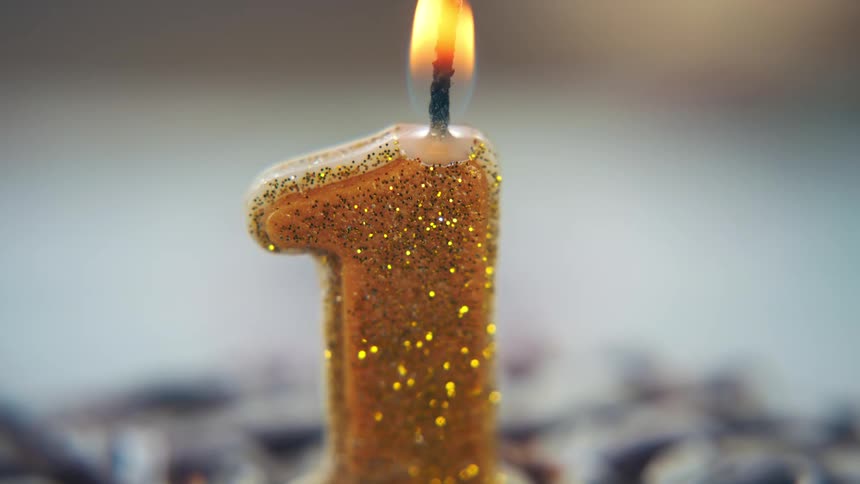 Golden number one candle lit on a cake