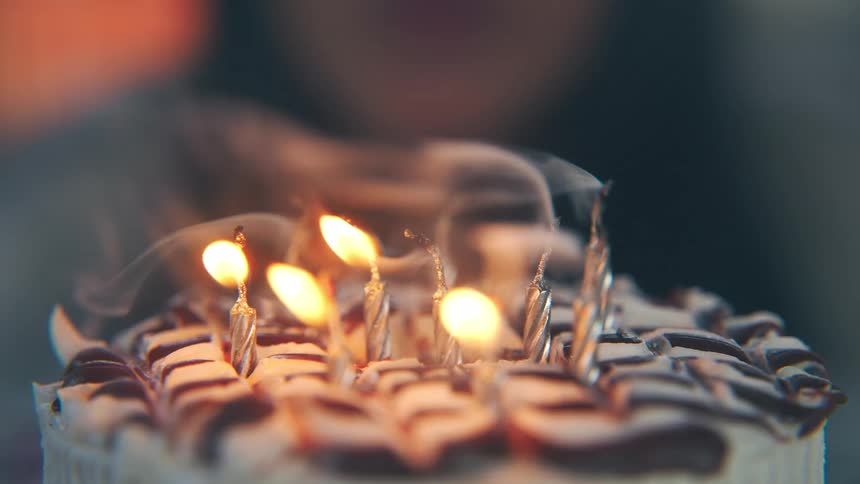 The girl blows out the candles on the birthday cake