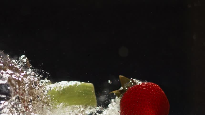 Fruit falls into water in a dark area