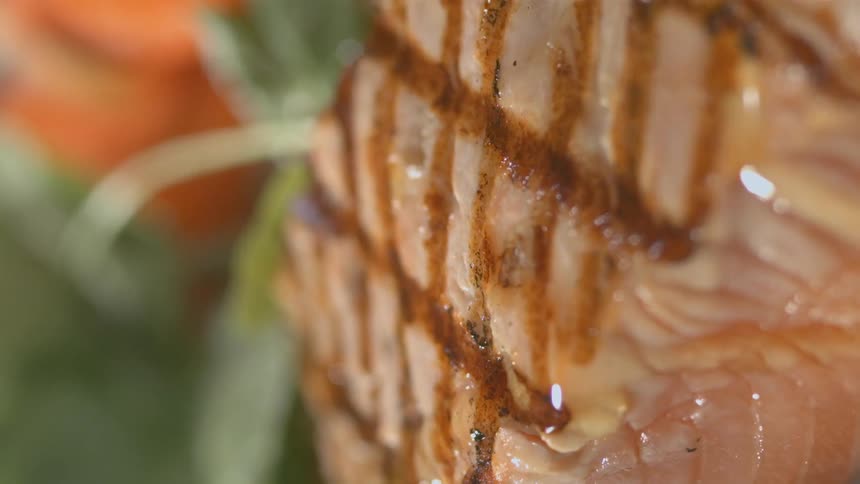 Dressing pouring onto salad next to grilled salmon