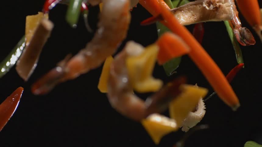 A bunch of vegetables and shrimp are thrown into the air