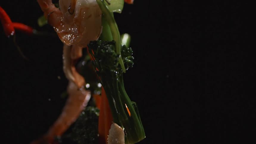 Vegetables and seafood are tossed in a pan