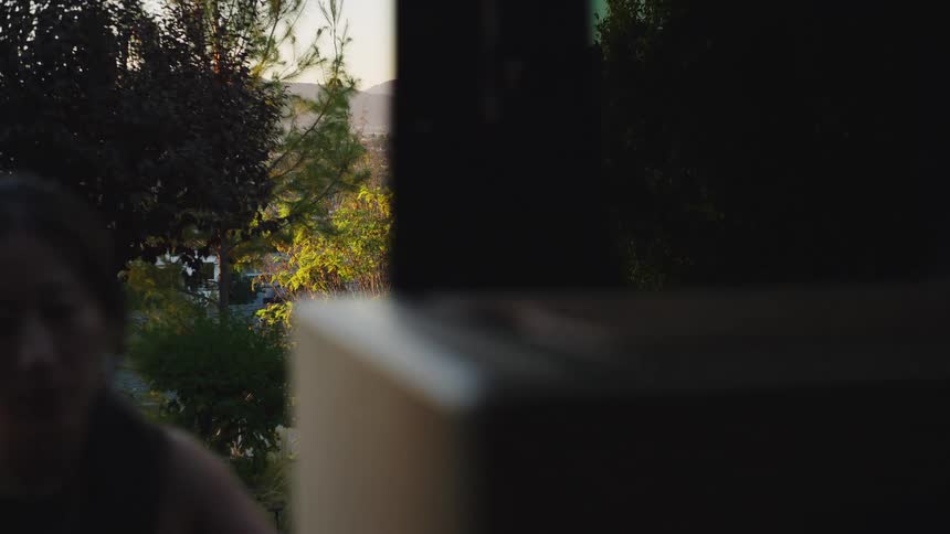 A woman opens a sliding glass door of a building in a residential neighborhood
