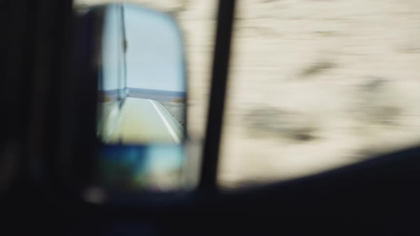 A van is traveling down a road through a high desert mountain range