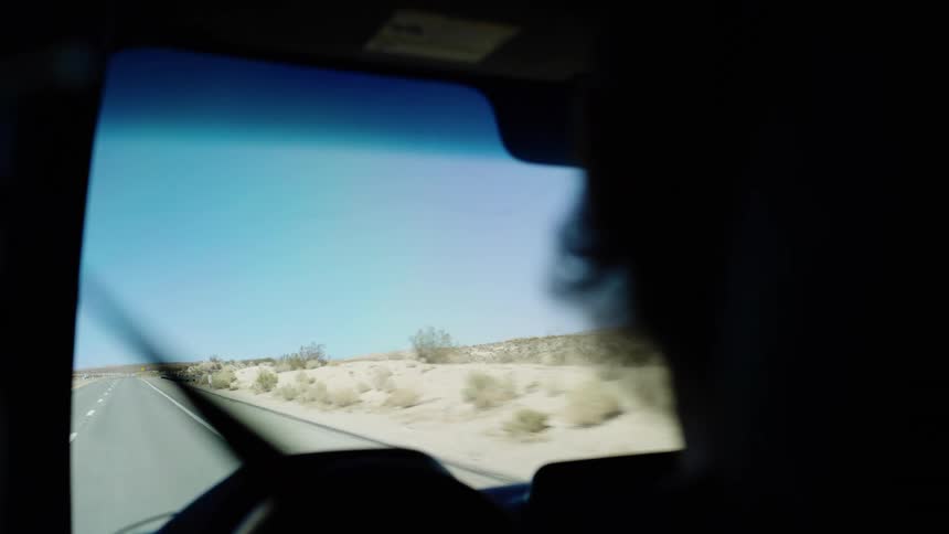 A person drives a car through the countryside on a sunny day