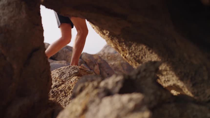 A man walks past a cave at the top of a mountain