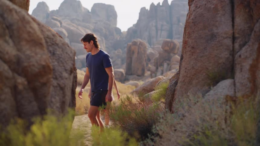 A couple walks across a rough rocky formation in the wild during a hike at midday