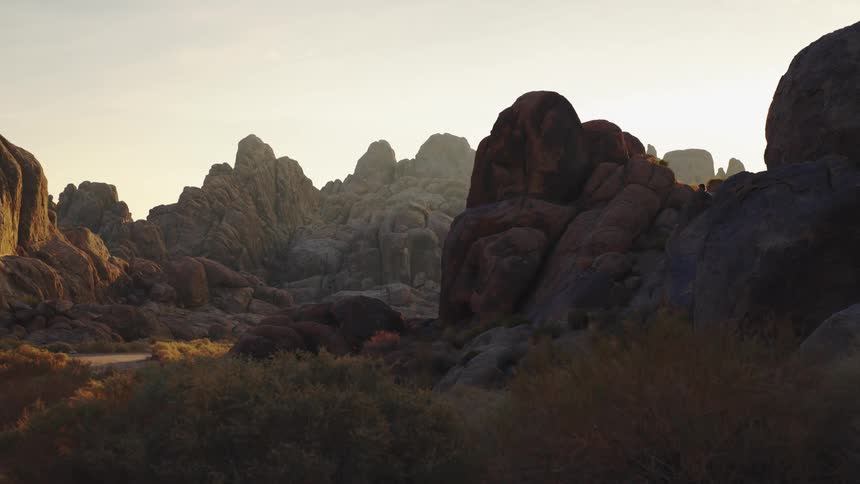 A man is seen in the distance hiking on a rocky mountainous formation on a sunny day