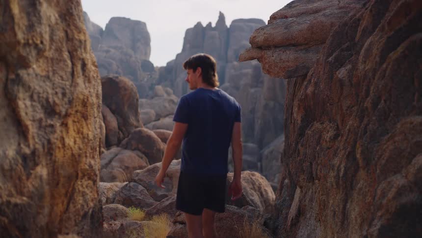 Man walks among rock formations in an arid canyon