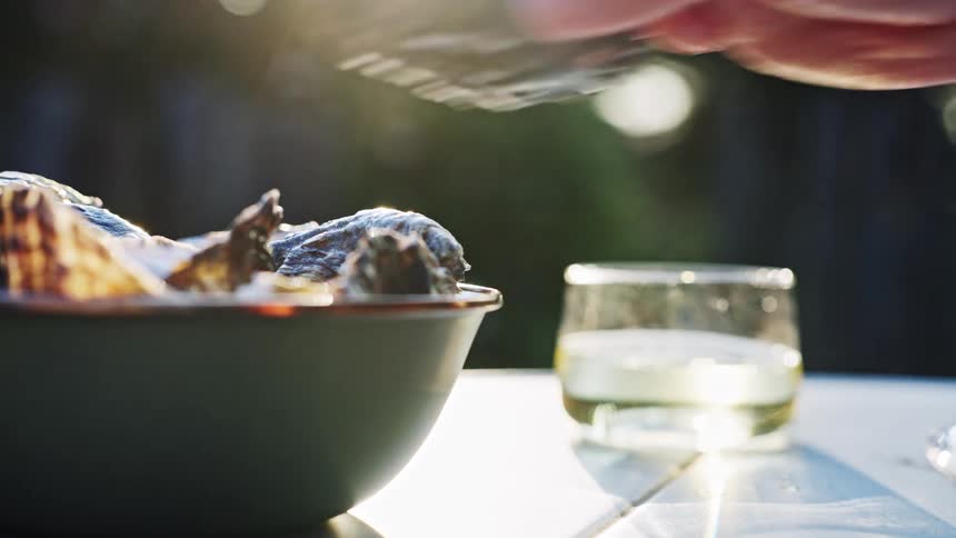 The woman puts an empty oyster shell in the bowl