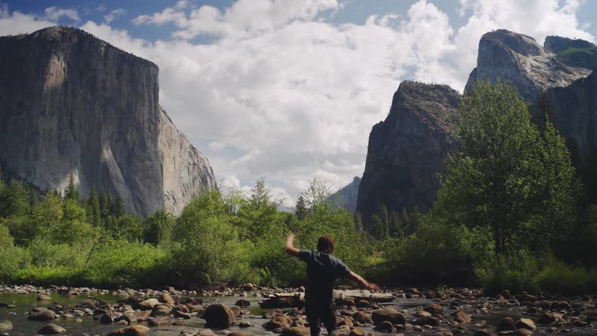 The man climbs over the rocks in the creek