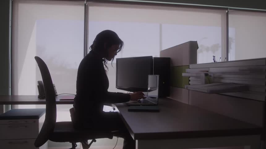 A woman focuses on her work while using a laptop at a desk in a modern office