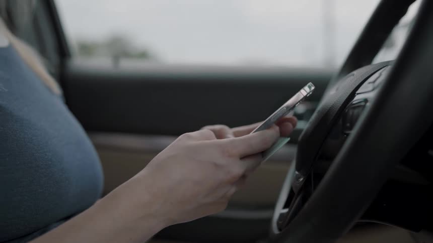 Person using a cellphone while sitting in the drivers seat