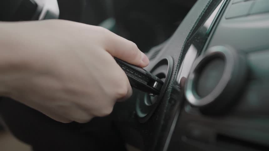 Hand turns the key in the ignition of a modern car