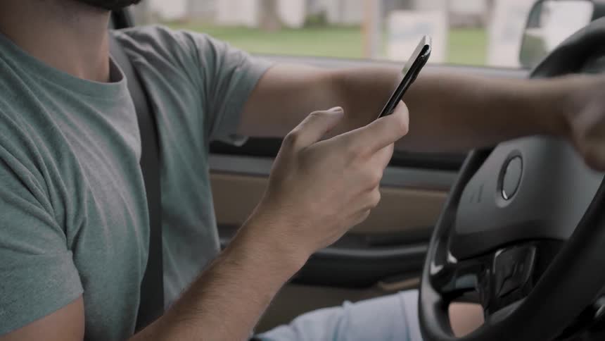 A man is driving erratically while looking at his cellphone