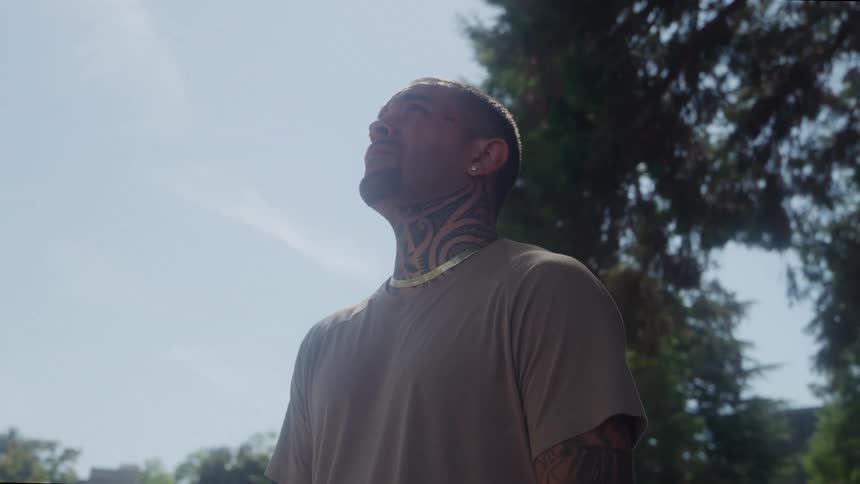 The man is looking up at the sunny sky