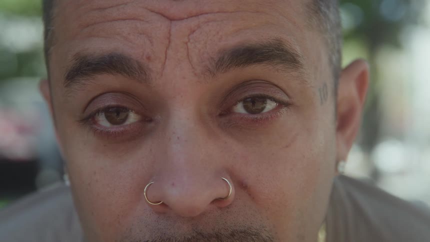 Face of a hispanic man with a moustache wearing face jewelry outdoors during day time