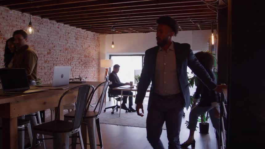 Professionals move around a modern office with natural light and rustic decor