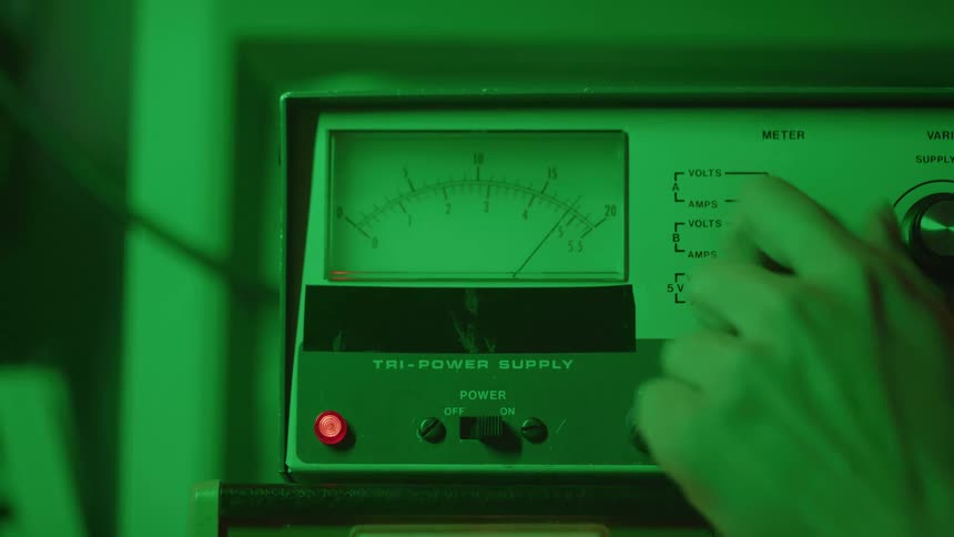 A person is turning a knob on a machine making the needle jump