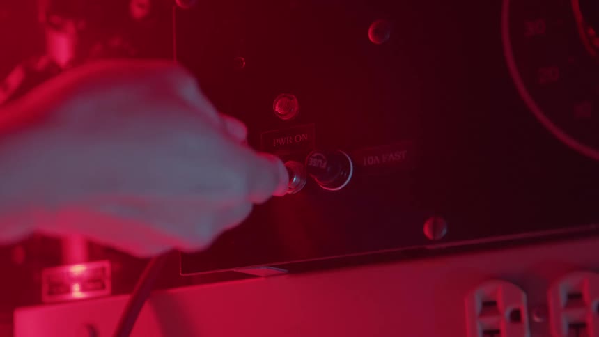 Hand flips a metal switch under intense red lighting