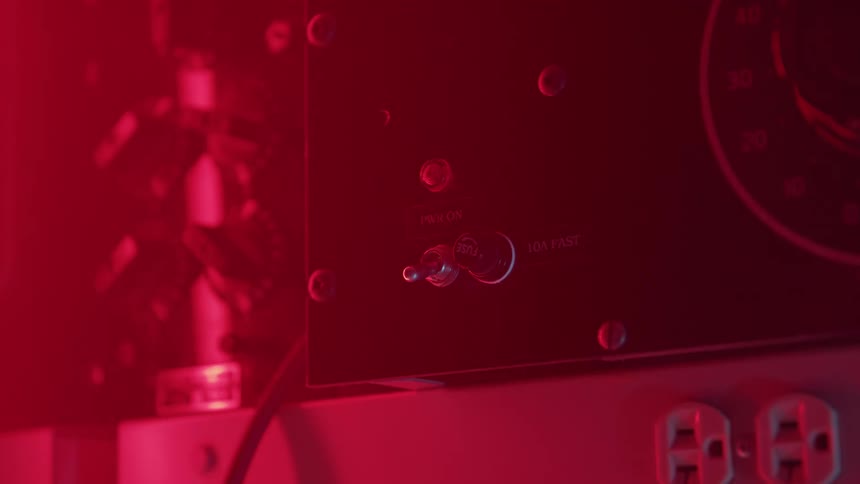 Hand switches on a metal device under intense red lighting