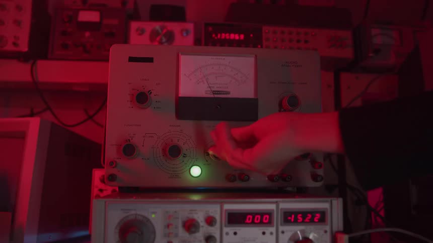 Person turns on one of the analog and digital devices in an area lit by red lighting