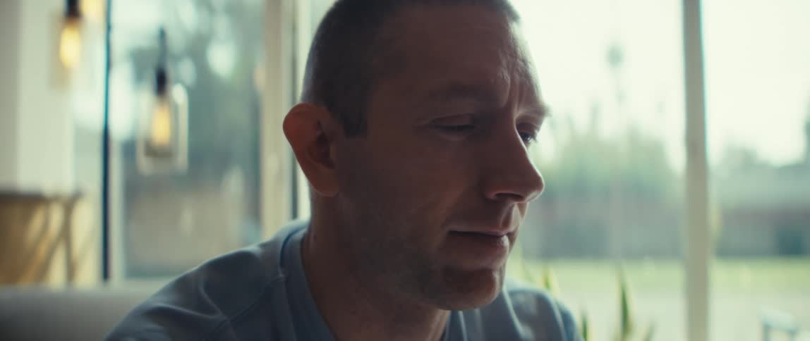 Man looking down with a serious expression in a welllit room