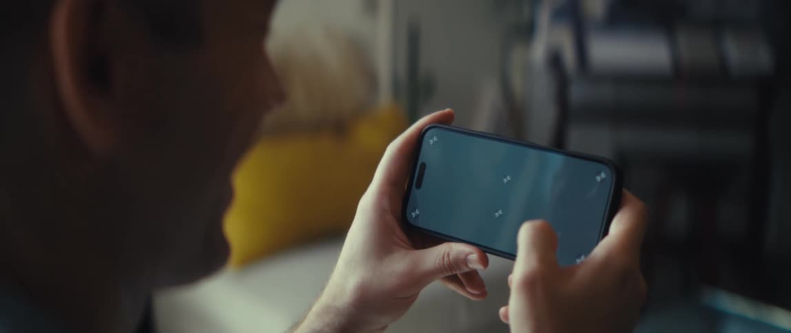 Man holds a smartphone horizontally while gaming indoors