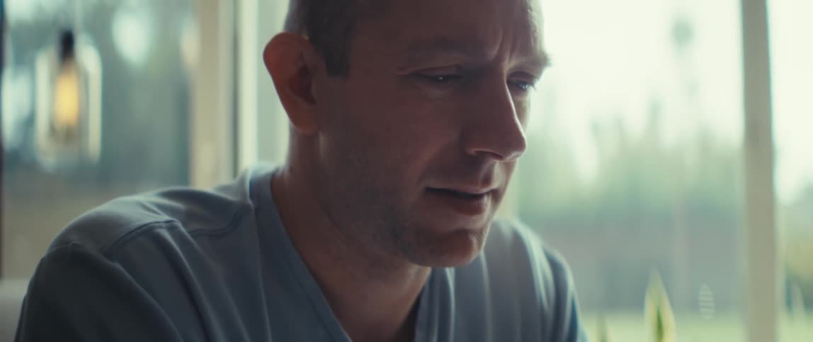 Man in gray shirt holds phone in natural light room