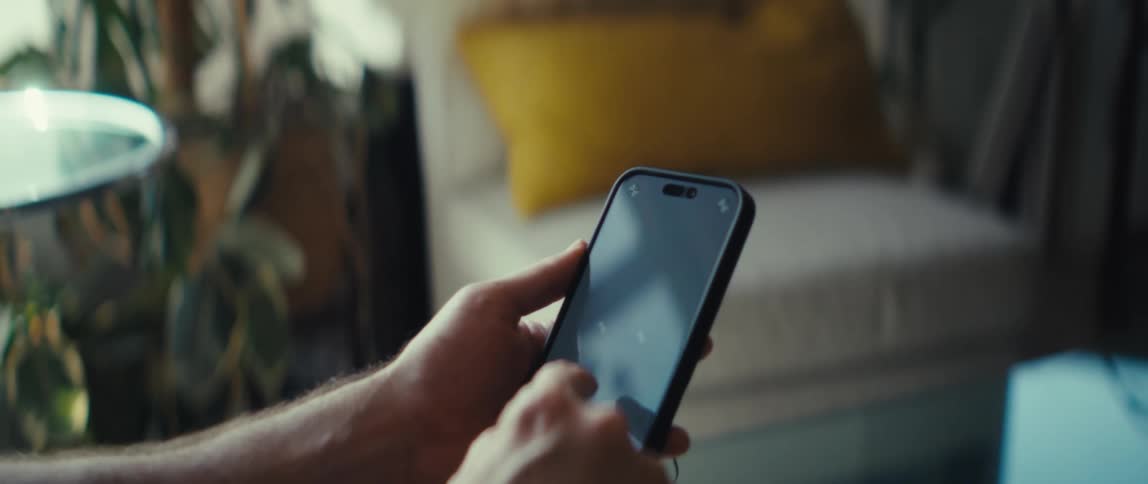 Person holds a smartphone and taps the screen in a welllit indoor setting