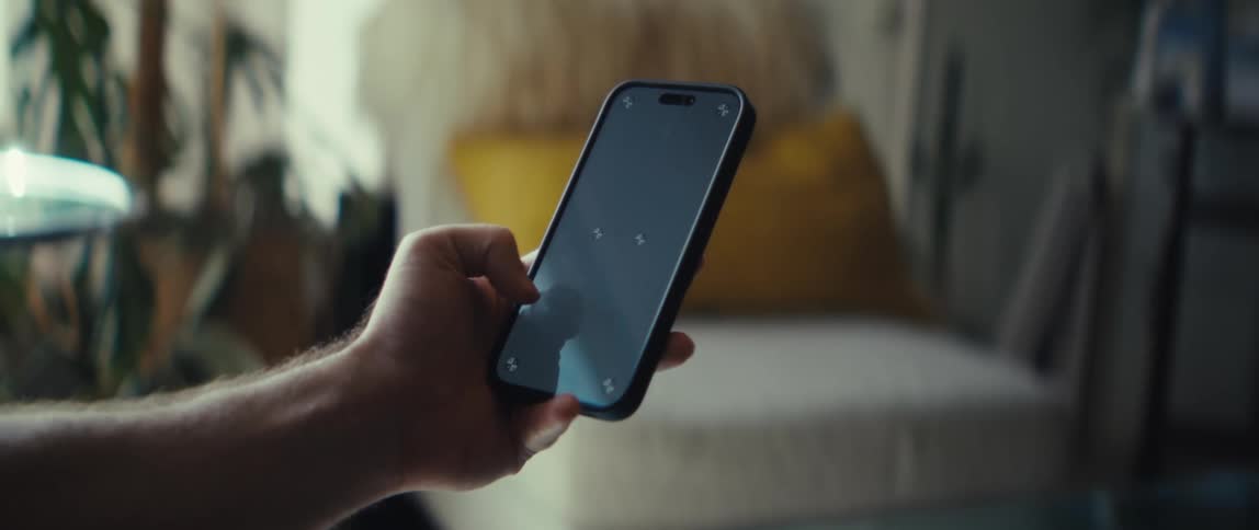 A closeup of hands holding a smartphone while gaming in a cozy living room