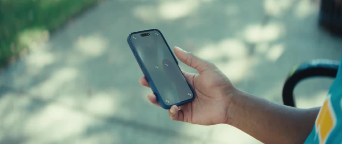 The man is sitting on a bench and holding his cell phone