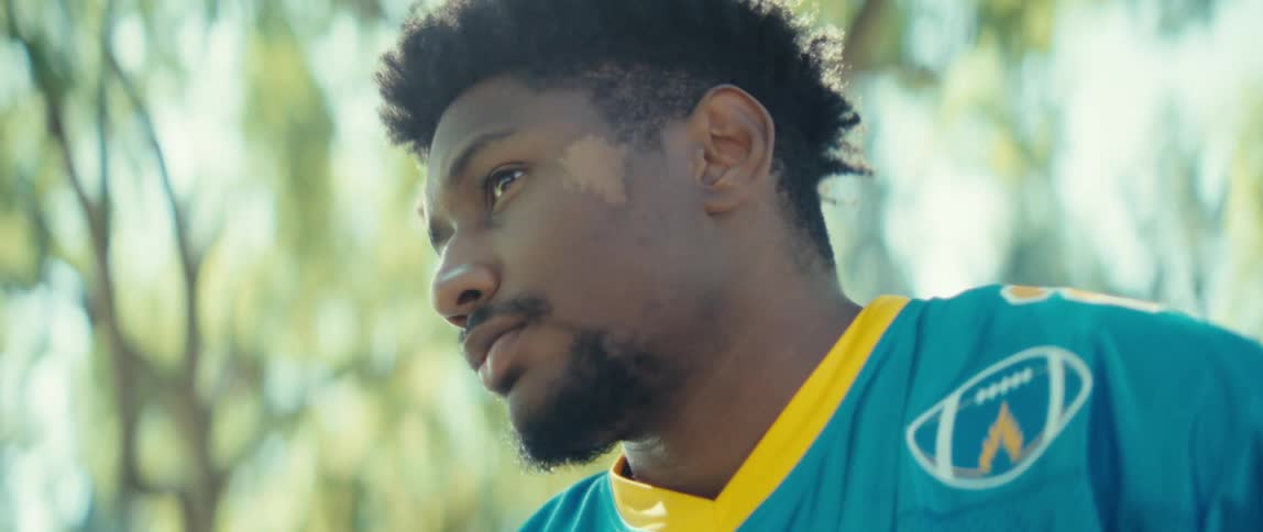 Man in a blue sports jersey holds a smartphone while looking at the screen